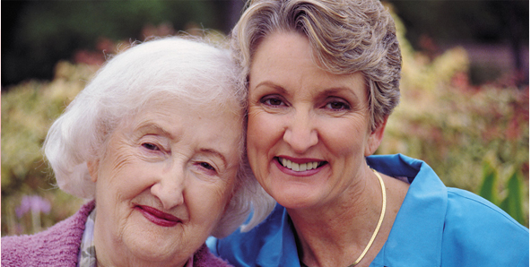 A middle aged woman and a senior woman smiling together