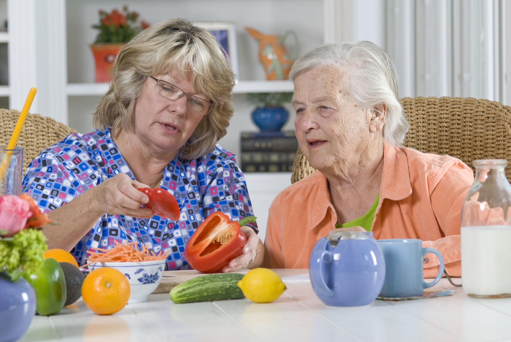 A caregiver helping a senior woman with meal preparation