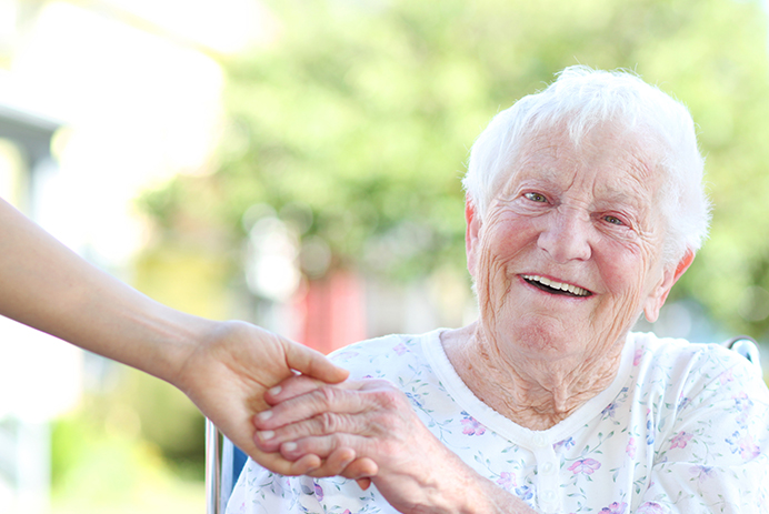 A smiling senior hold the hand of a caregiver