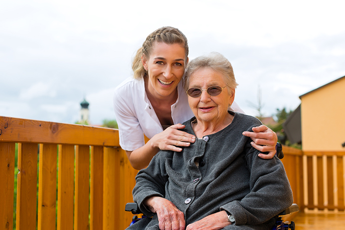 An in-home caregiver and a senior on a deck