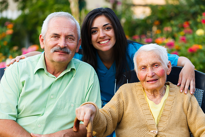 A caregiver sitting with a smiling senior couple