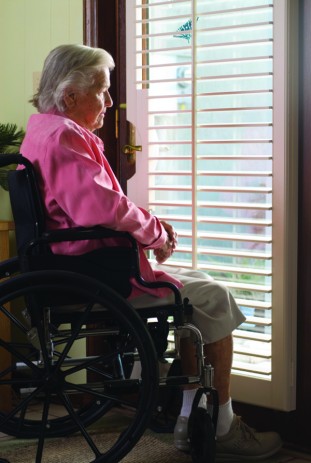 An elderly woman in a wheelchair looks outside