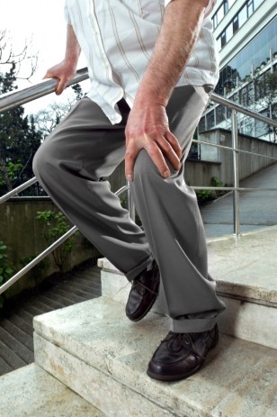 A senior struggles to walk down a flight of stairs